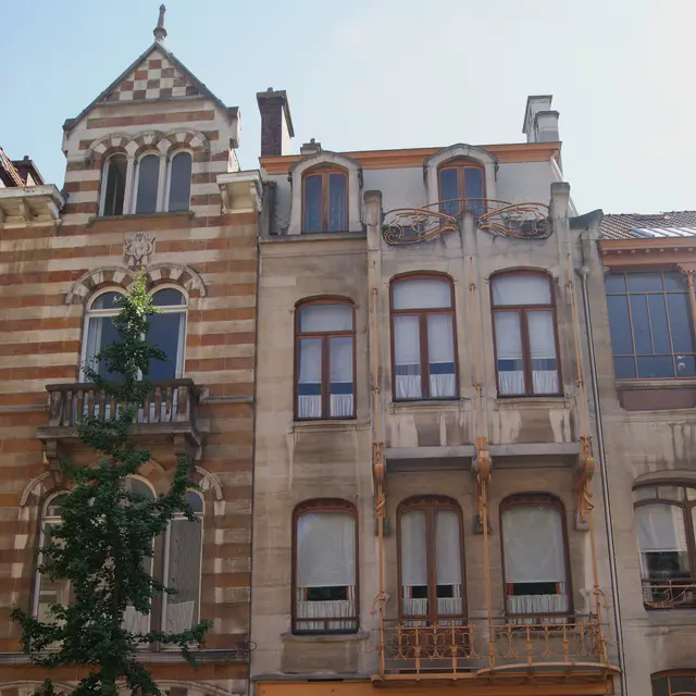 rue AméricaineにあるHortaの邸宅の、鉄のバルコニーと彫刻を施した木製の扉を備えた狭い石造りの正面
